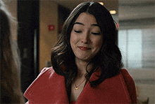 a woman is wearing a red coat and a necklace