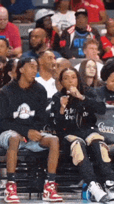 a woman is sitting in the stands at a basketball game while a man looks on .