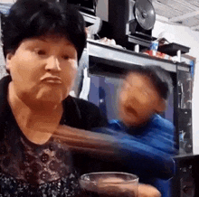 a woman is sitting at a table holding a glass of soda and making a face .