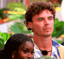 a man with curly hair is standing next to a woman who is wearing earrings