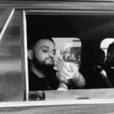 a man with a beard is sitting in a car holding a piece of paper .