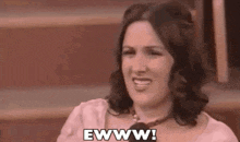 a woman is sitting in front of a microphone and smiling while saying ewww .