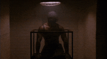 a man is standing in a dark room with a light hanging from the ceiling