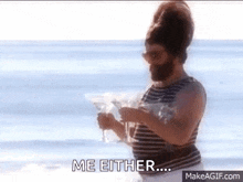 a man with a beard is standing on the beach holding a martini and says me either