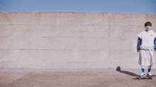 three young men are standing on skateboards in front of a wall and one of them is wearing a white shirt with the letter a on it
