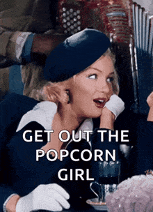 a woman sitting at a table with the words get out the popcorn girl on the bottom