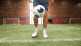 a man is kicking a soccer ball on a field with a sign that says sports academy in the background
