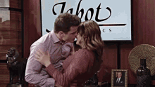a man and woman are kissing in front of a sign that says jabot cs