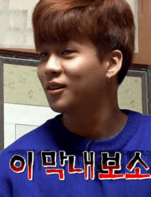 a young man wearing a blue sweater with korean writing