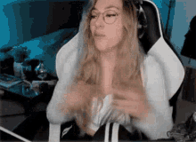 a woman wearing glasses is sitting in a chair in front of a computer .