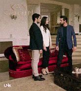 three people standing in front of a red couch with kan cicekleri written above them