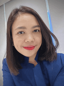 a woman wearing a blue jacket and red lipstick smiles at the camera