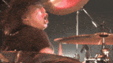 a man playing a drum set with the letter d on the bottom right
