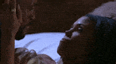 a man and woman are laying on a bed and kissing .