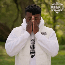 a man wearing a canada 's ultimate challenge vest covering his face with his hands