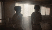 two people standing in front of a window with the sun shining through