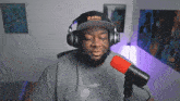a man wearing headphones and a bath hat stands in front of a microphone