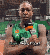 a man in a green adidas jersey is holding a microphone in front of him