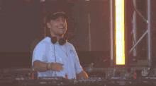 a man wearing headphones stands in front of a pioneer dj