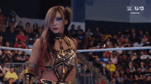 a woman is standing in a wrestling ring with a crowd behind her .
