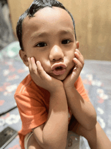 a little boy making a funny face with his hands on his face
