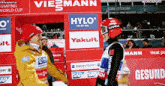 two athletes shake hands in front of a sign that says hylo