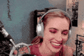 a woman wearing headphones is smiling in front of a microphone in a room