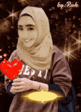 a woman in a hijab is holding a red heart and wearing a shirt that says jesus on it