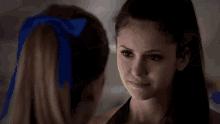 a cheerleader with a blue bow in her hair is talking to another cheerleader