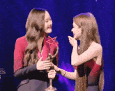 two women standing next to each other with one holding a star shaped trophy