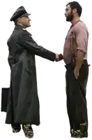 a man in a black coat shakes hands with another man in a pink shirt