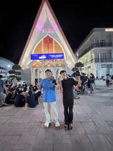 two men standing in front of a church that says tin lam