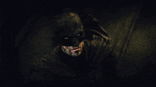a close up of a man in a batman costume in the dark