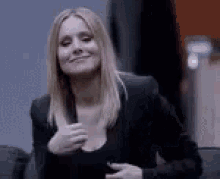 a woman in a black suit is giving a thumbs up .