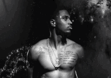 a black and white photo of a shirtless man with tattoos