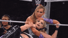 two women are wrestling in a ring with a w logo on the wall behind them