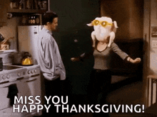 a man and woman are dancing in a kitchen with a turkey on their head .