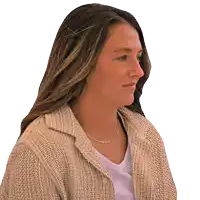 a woman wearing a sweater and a necklace looks to her left