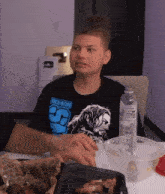a man wearing a roman t-shirt sits at a table