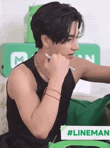 a man wearing a black tank top is holding a pen in his hand