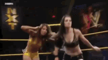 two women are wrestling in a ring with a referee watching .