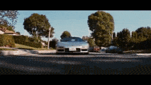a silver sports car with a california license plate is driving down the street