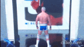 a man in blue shorts is standing in front of a screen that says ' clideo.com '