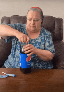 a woman is opening a bottle of pepsi sitting in a chair