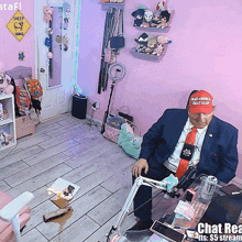 a man wearing a hat that says make america great again sits at a desk