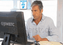 a man is sitting in front of a computer screen that says @jimbtc