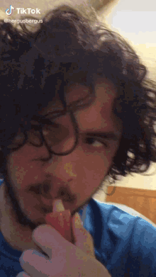 a man with curly hair and glasses has a tiktok sticker on his face
