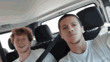 two men are sitting in the back seat of a car and one is wearing a t-shirt that says abercrombie