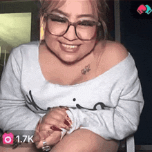 a woman with glasses and a tattoo on her shoulder has 1.7k followers on her account