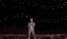 a woman in a silver dress is dancing on a stage .